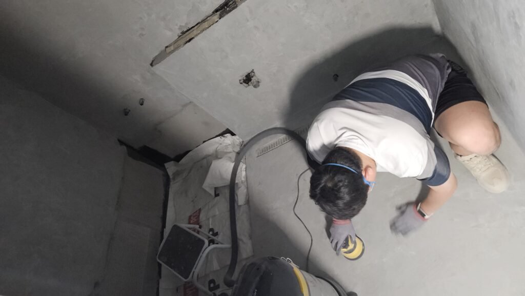 방진마스크를 쓰고 전동 샌더로 베이스코트 벽면을 샌딩하는 모습