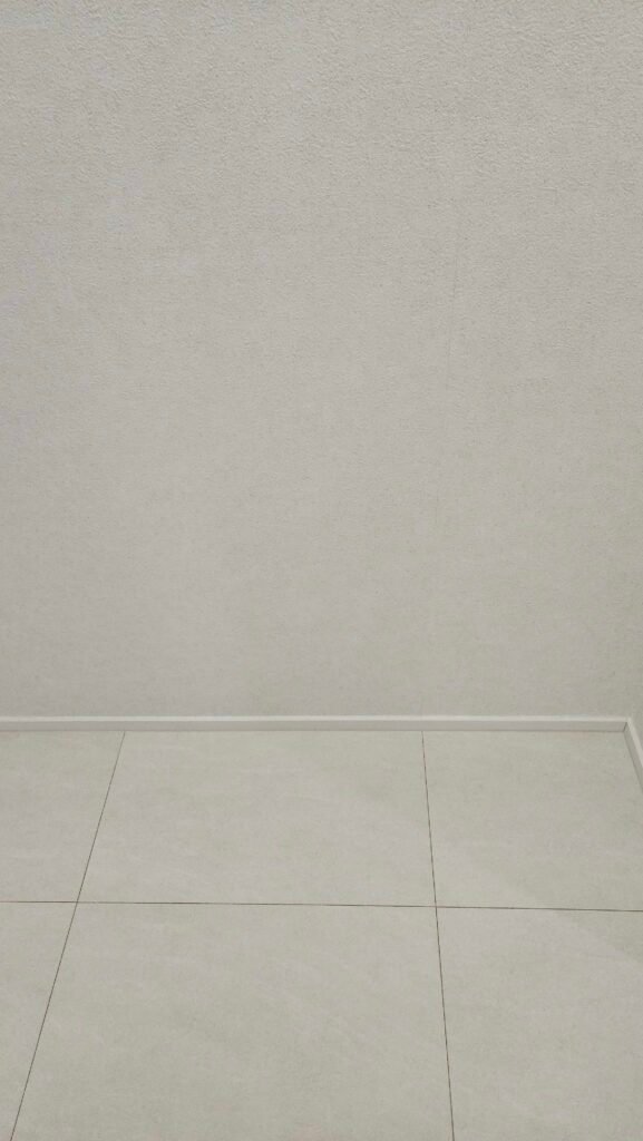 흰색 벽지와 걸레받이, 바닥재가 만나는 벽 모서리