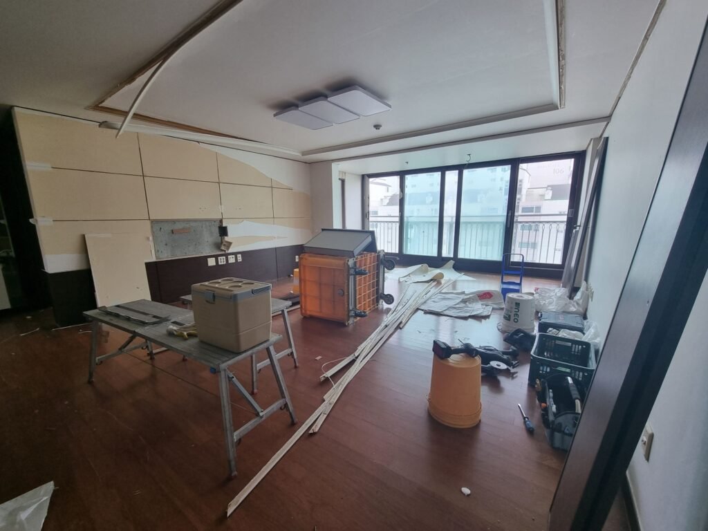 천장 몰딩 일부와 바닥재가 뜯겨 어수선한 철거 초기 단계의 거실